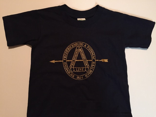 Photograph of dark blue t-shirt with gold lettering. Lettering is of the circular logo applied to RF&P steam engine tenders.