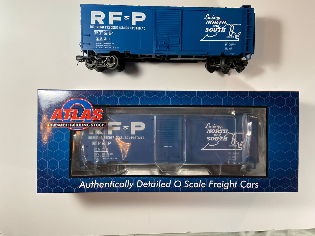 Photo of two O gauge blue Pullman Standard boxcar painted for RF&P railroad. One boxcar is in a blue cardboard box labeled Atlas. The other is seen out of its box.